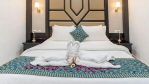 A neatly made bed with a decorative towel arrangement, a patterned bedspread, and a headboard with geometric design. - Gardenia Park Al Rawabi Serviced Apartments Economy (Jeddah)