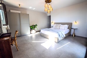 Une chambre à coucher moderne avec un grand lit, une chaise en bois, une plante en pot et un bureau.