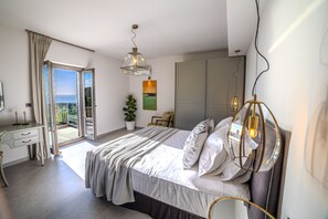 Une chambre à coucher comprenant un lit, un bureau, une chaise, une plante en pot et une vue sur l’extérieur.