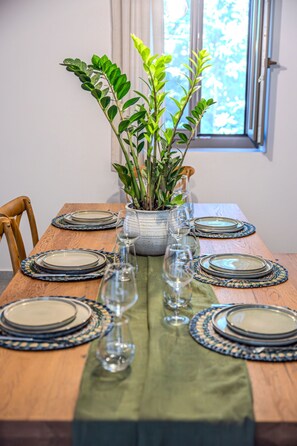 Une table à manger dressée avec des assiettes, des verres et une plante en pot.