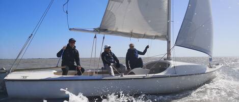 A sailboat with two people on deck, one holding a rope.
