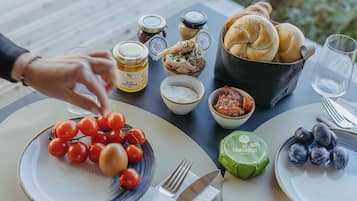 Una mesa dispuesta con diversos alimentos, como tomates, pan y queso, que sugiere una comida al aire libre.
