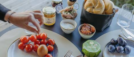 Una mesa dispuesta con diversos alimentos, como tomates, pan y queso, que sugiere una comida al aire libre.