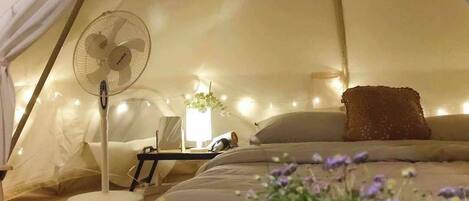 Una carpa con una cama, un ventilador y luces de cadena.