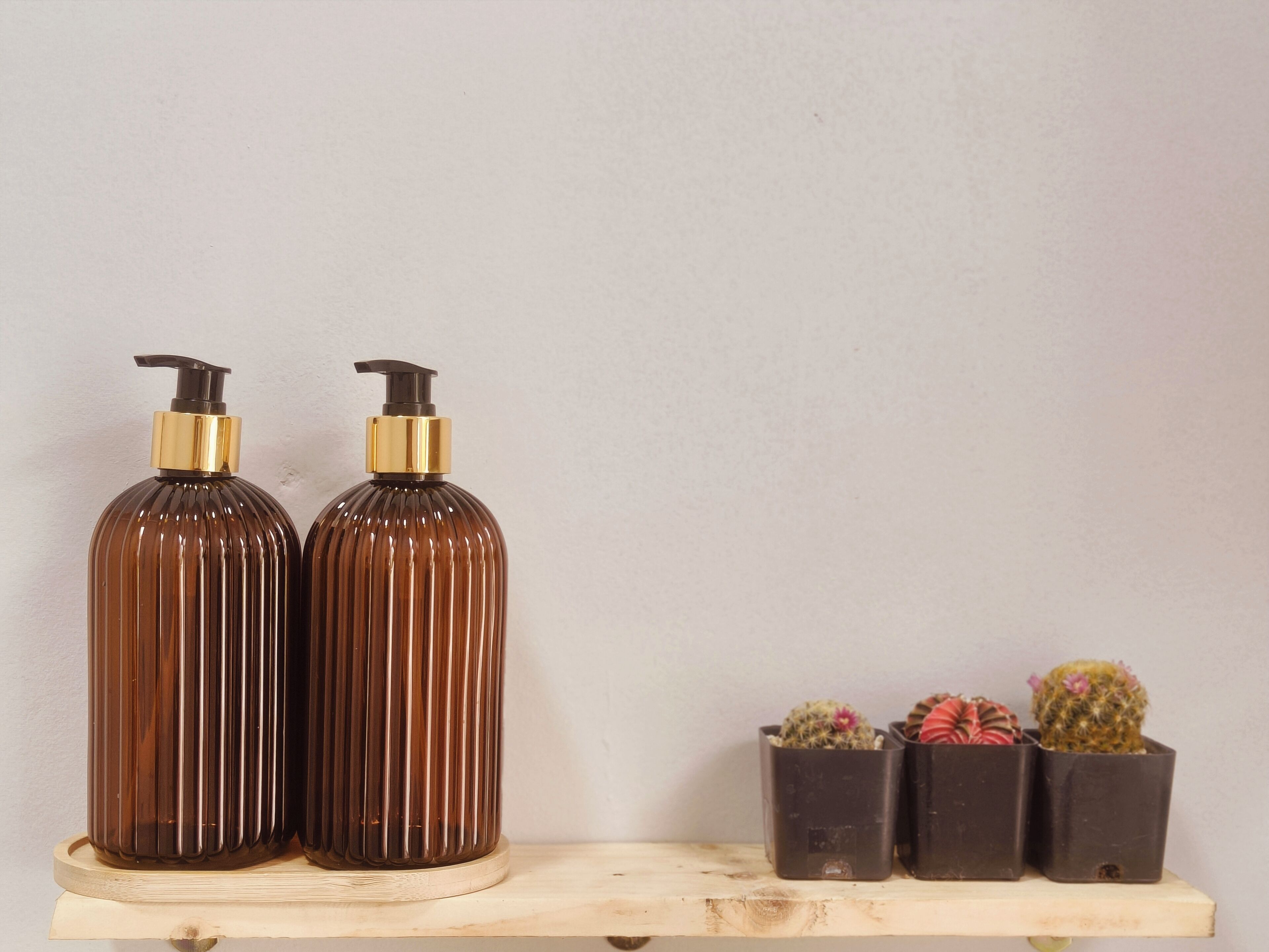 Two brown bottles with gold accents on a wooden shelf.