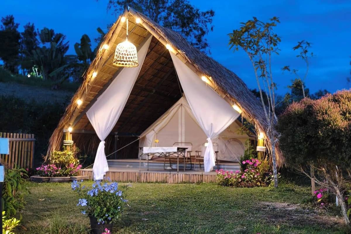 Una carpa con techo de paja, un área de comedor y una lámpara colgante.