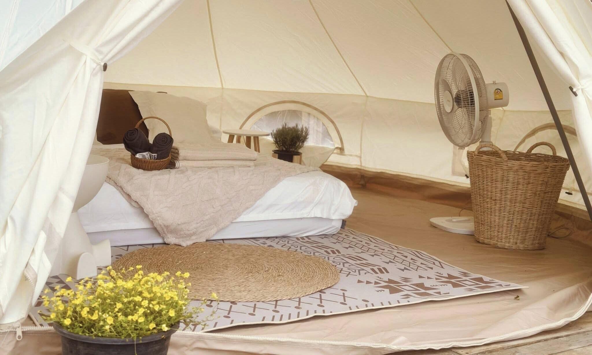 A cozy tent with a bed, a fan, and a basket.
