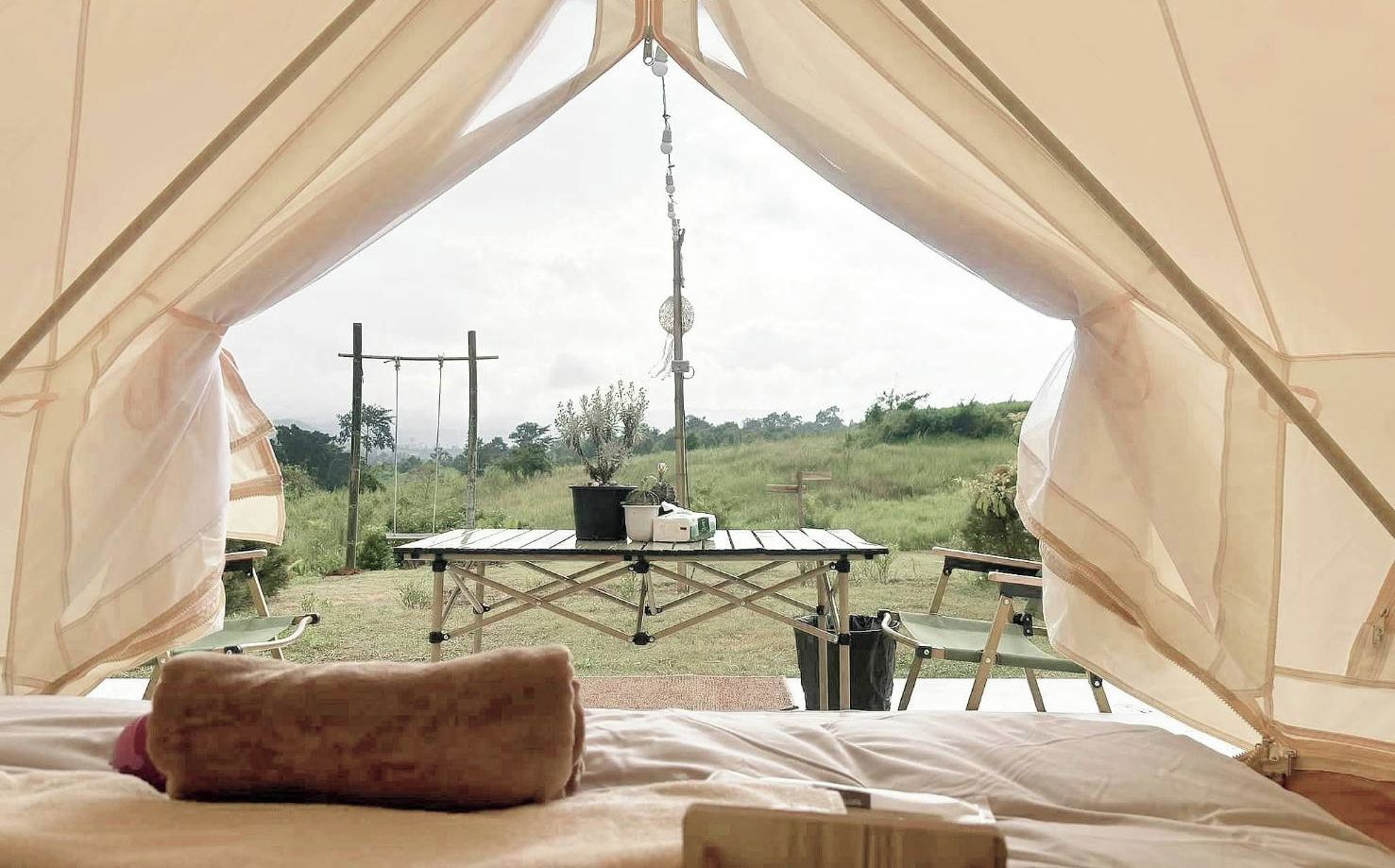 A tent with a bed inside, a table, and chairs outside.