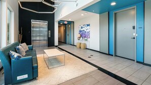 A modern lobby with a blue sofa, a coffee table, and a large painting on the wall. - Riverscape Townhome (Baton Rouge)