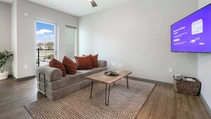 A modern living room with a grey sofa, a wooden coffee table, and a flat-screen TV mounted on the wall. - Riverscape Townhome (Baton Rouge)