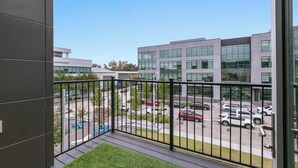 A modern building with a balcony overlooking a parking area and other buildings. - Peaceful Modern Townhome | Water Campus (Baton Rouge)