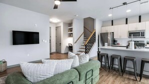 A modern kitchen with a built-in microwave, a stainless steel refrigerator, and a bar area with stools.