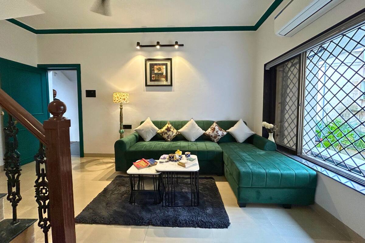 Una sala de estar con un sofá verde, una mesa de centro y una ventana con vistas.