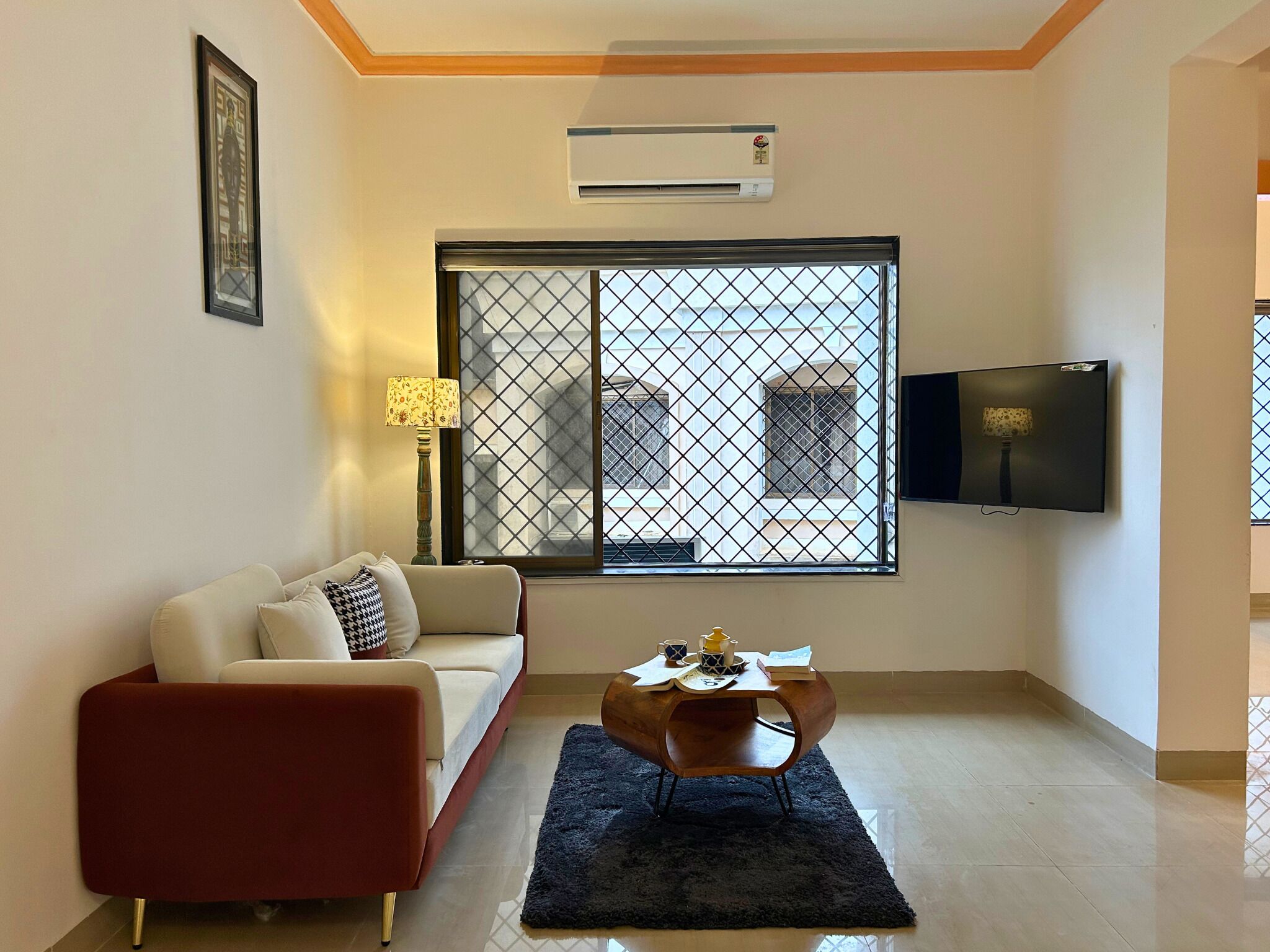 A living room with a sofa, a coffee table, a TV, and a window with a view of buildings.