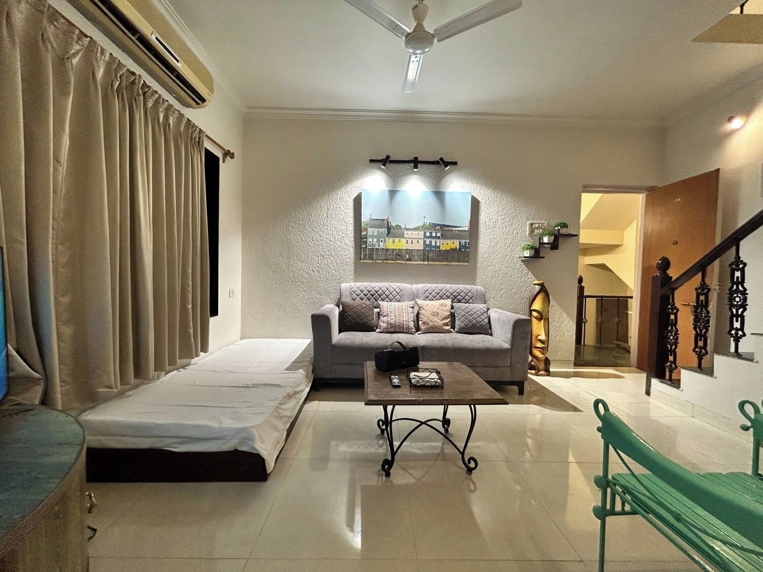 A living room with a sofa, a coffee table, a bench, a bed, and a staircase.