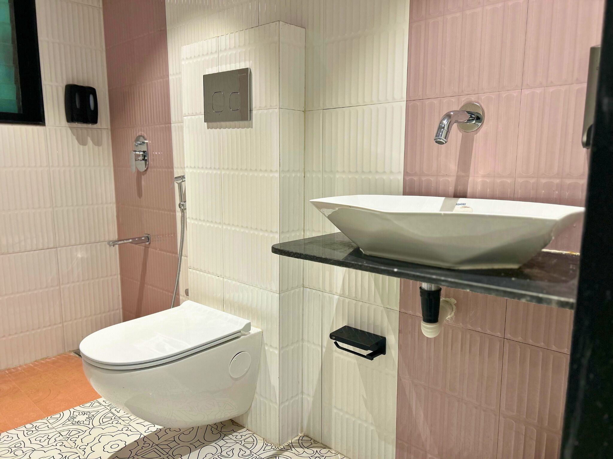 A bathroom with a white toilet, a white sink with a black countertop, and a shower area.