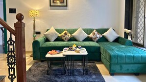Un salon avec un canapé vert, une table basse et un tableau encadré accroché au mur.