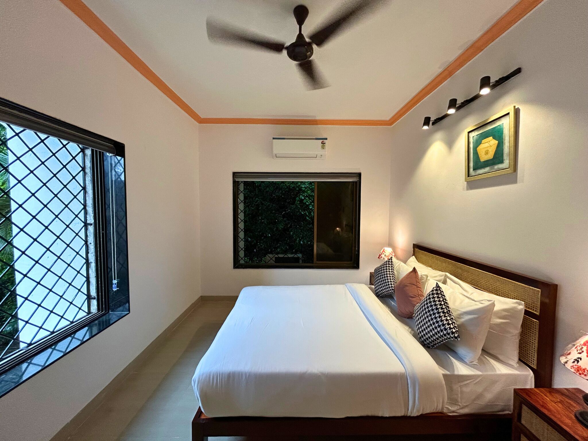 A bedroom with a bed, a ceiling fan, a window with a view, and a wall-mounted air conditioner.