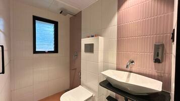 A bathroom with a toilet, sink, and window.
