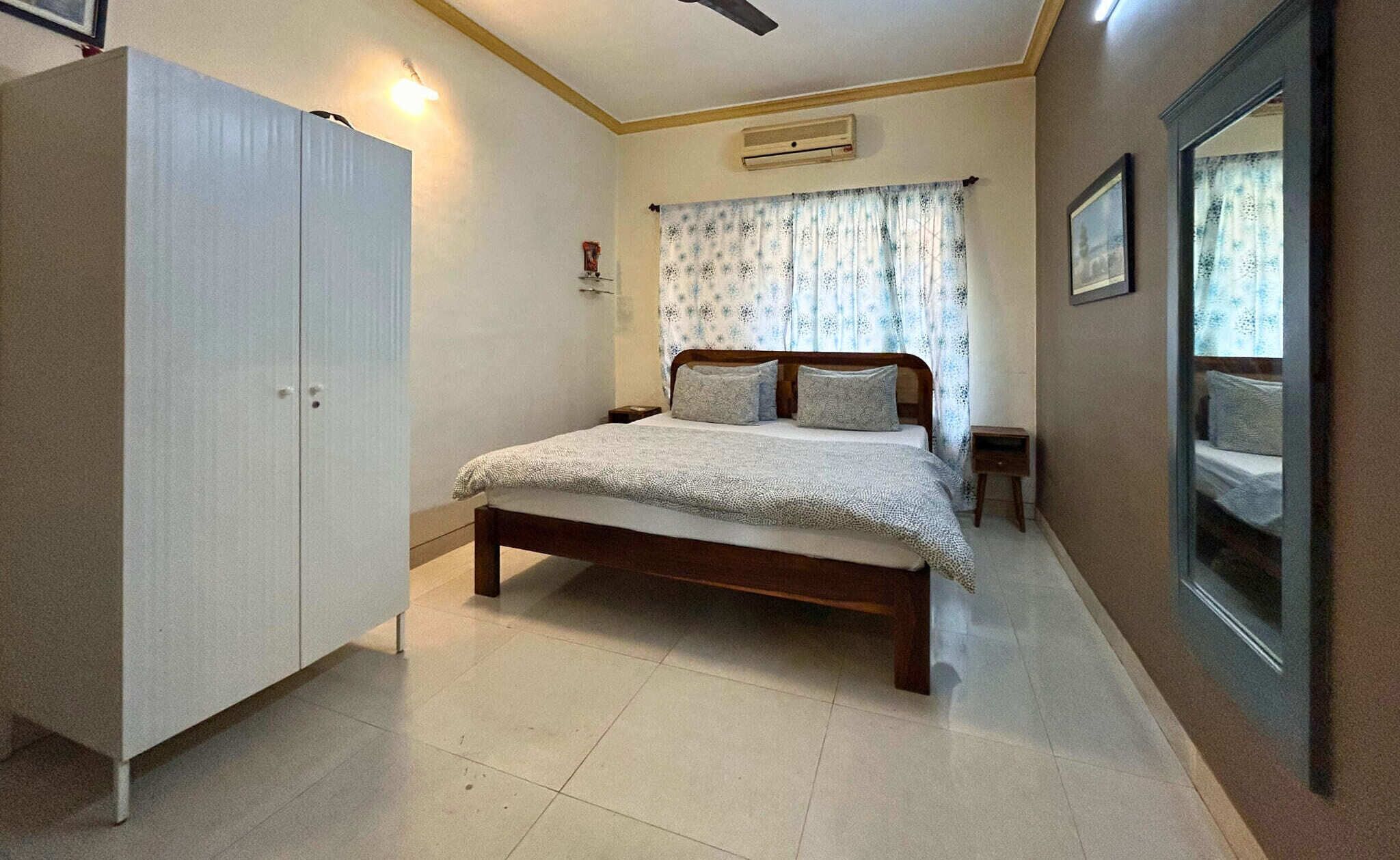 Een slaapkamer met een bed, een kledingkast, een nachtkastje en een spiegel.
