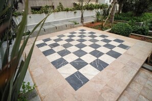 A checkered outdoor area with a white fence and greenery. - Domaine d'Anfa | Luxurious Appt | Pool & Sea (Casablanca)