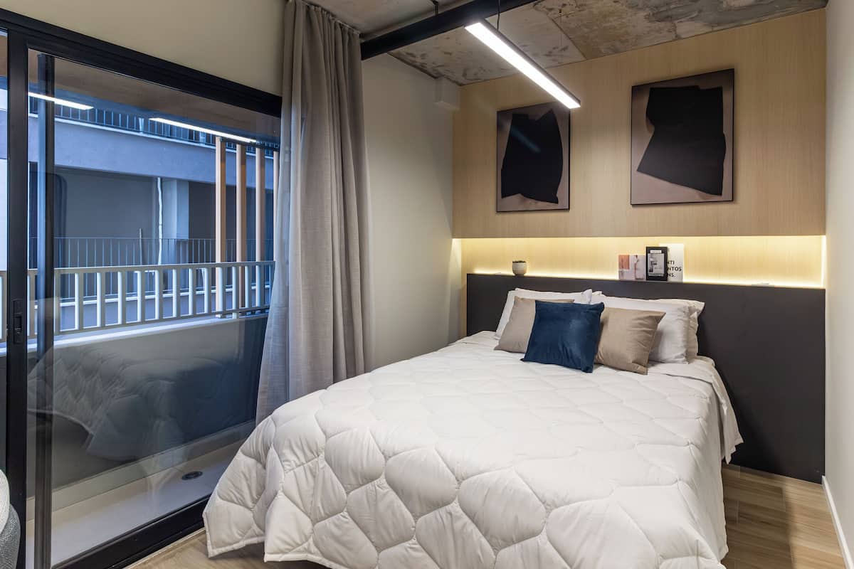 Ein Hotelzimmer mit einem großen Bett, einer Glastür zum Balkon und einem modernen Design mit Holzboden und Deckenbalken.