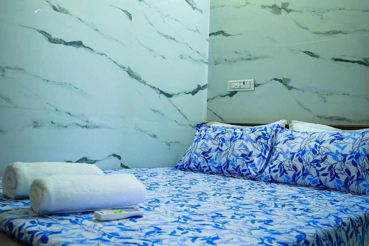 A room with a bed, a ceiling fan, and marble-patterned walls.