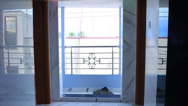 A spacious room with a large window, a balcony, and a marble floor. - RR RESIDENCY RANIPET (Walajapet)