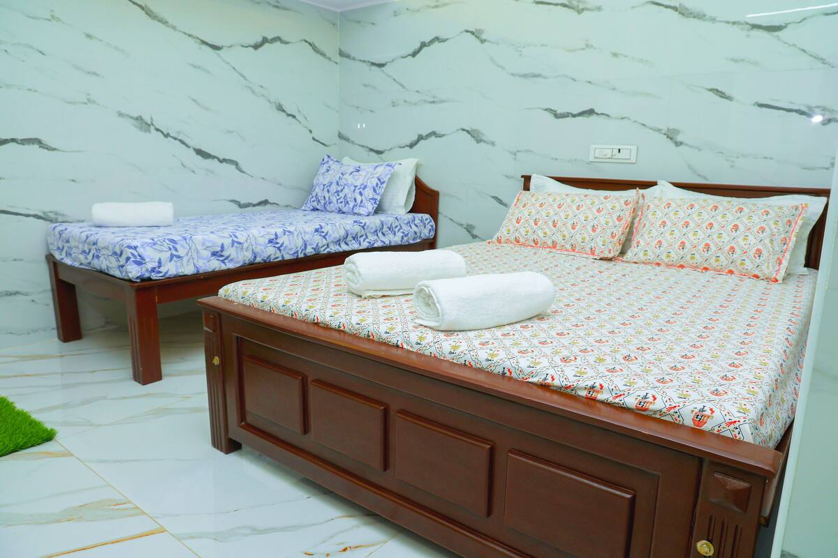 A bedroom with two beds, marble walls, and wooden furniture.