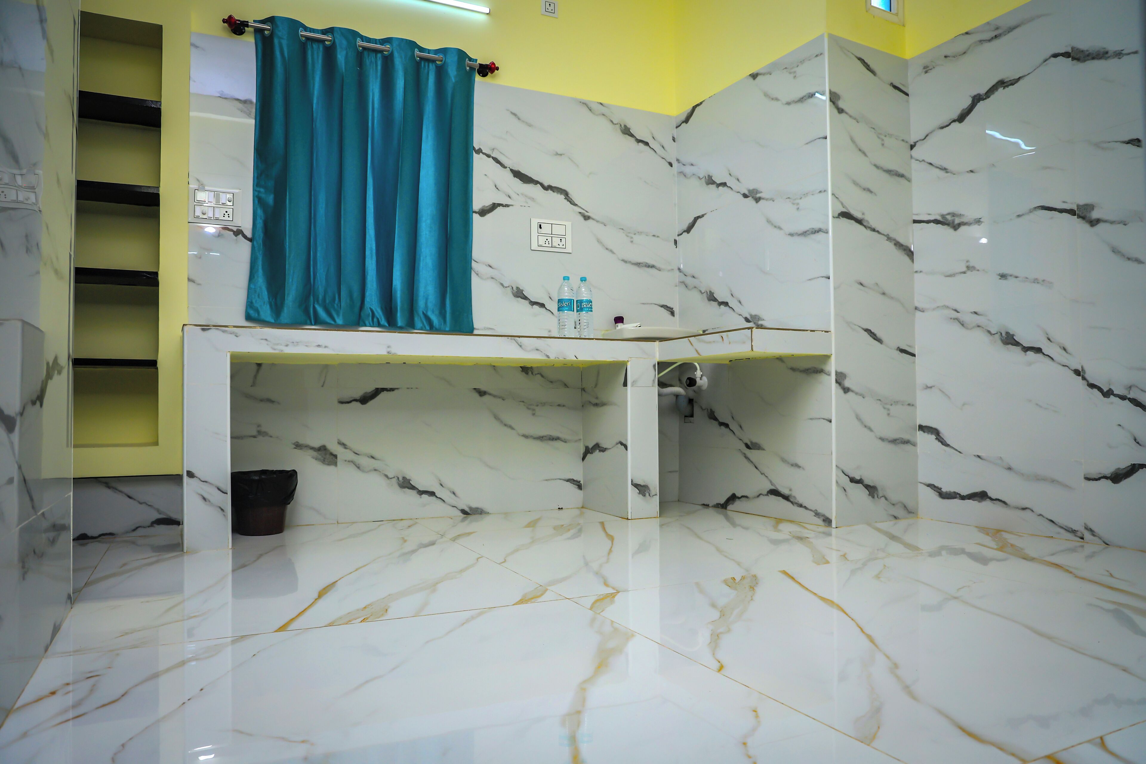 A bathroom with marble walls and floor, a sink, a shower, and a towel rack.
