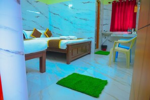 A bedroom with a bed, a green rug, a wooden nightstand, a mirror, and a window with a red curtain.