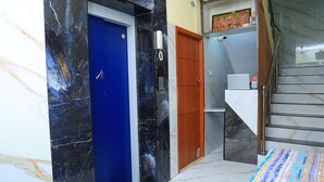 A hotel room with a marble floor, a blue door, a wooden door, and a staircase. - RR RESIDENCY RANIPET (Walajapet)