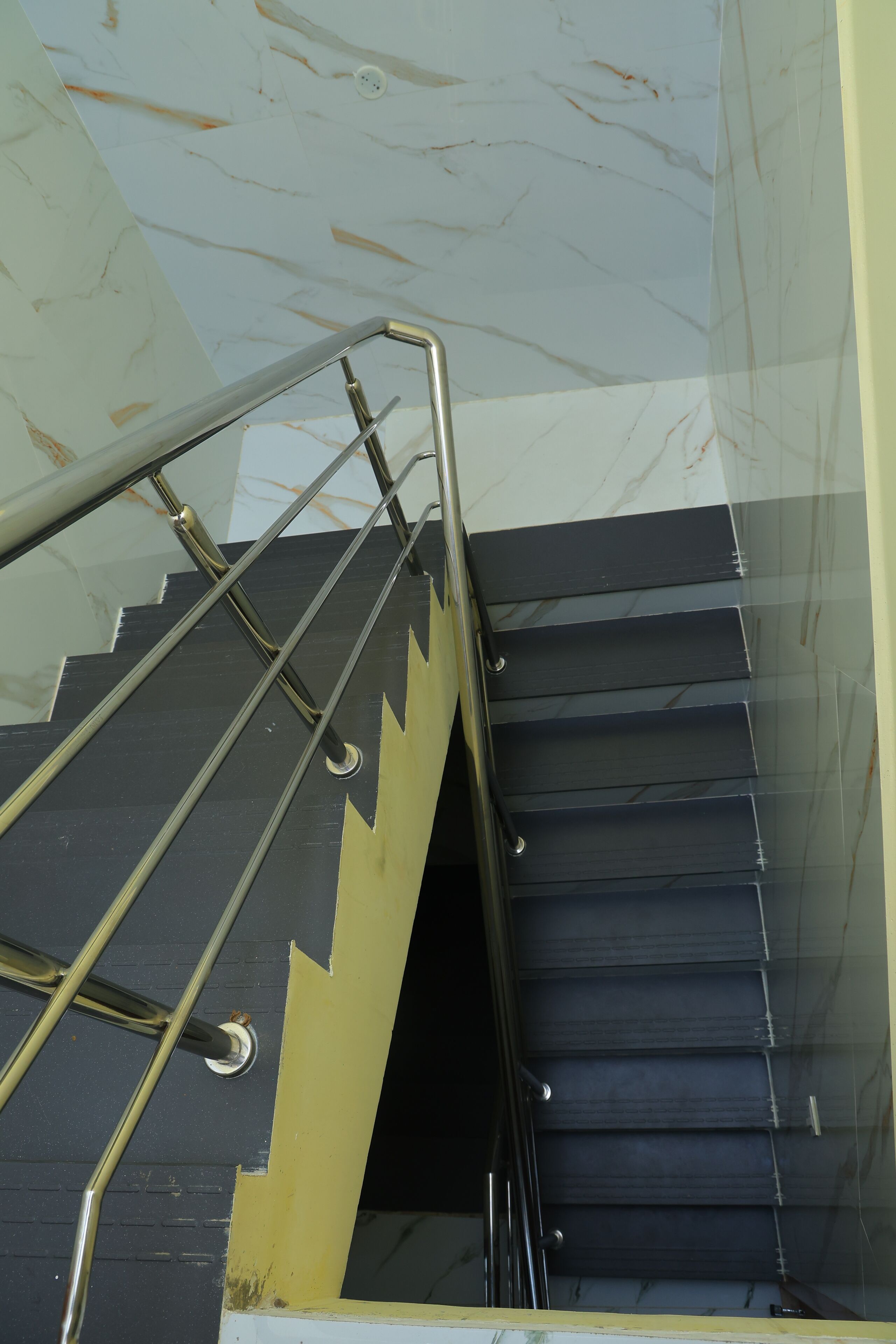 Una escalera con barandilla de metal y peldaños oscuros.