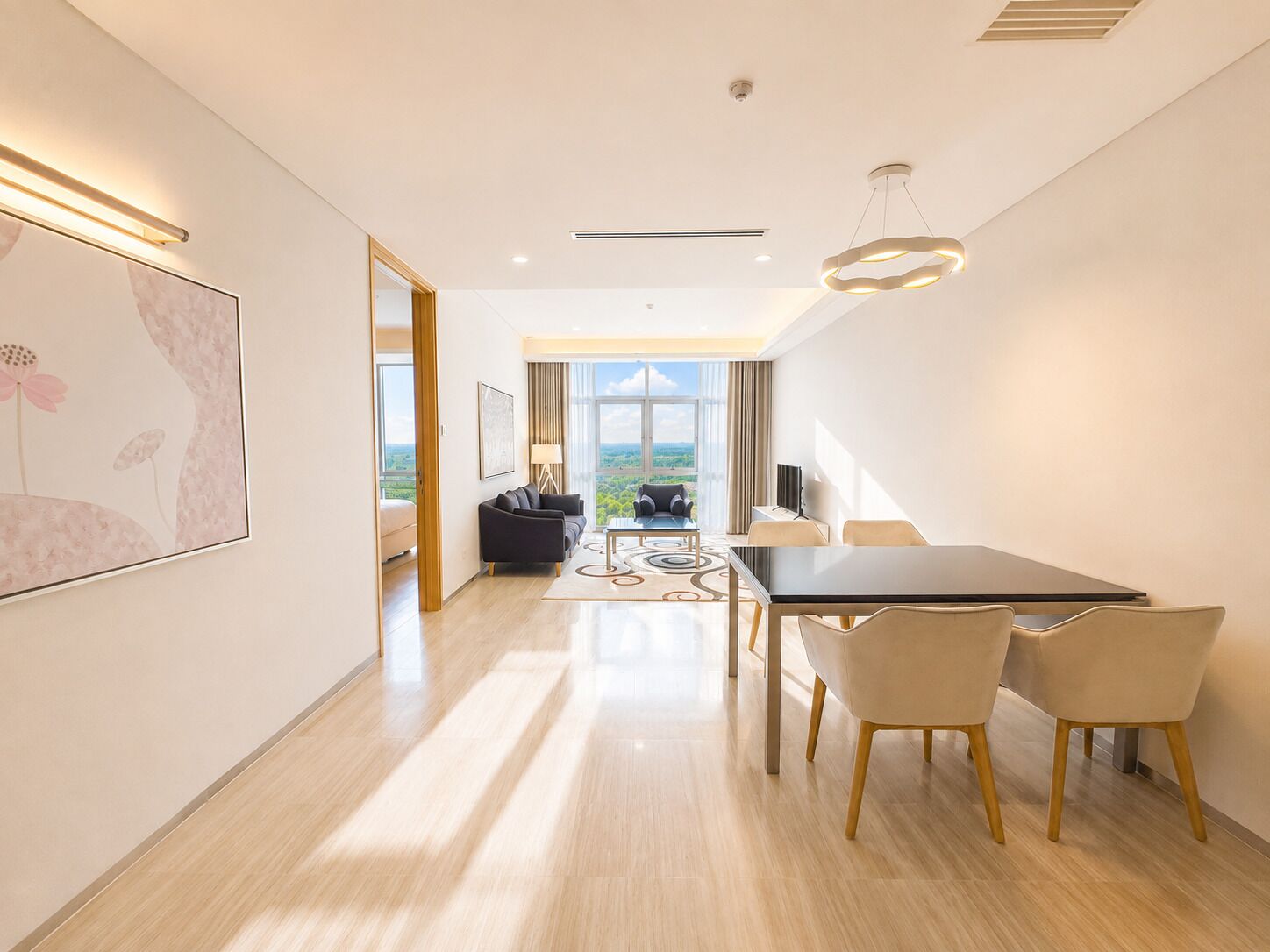 A modern hotel room with a dining area, a large window with a view, and a flat-screen TV.
