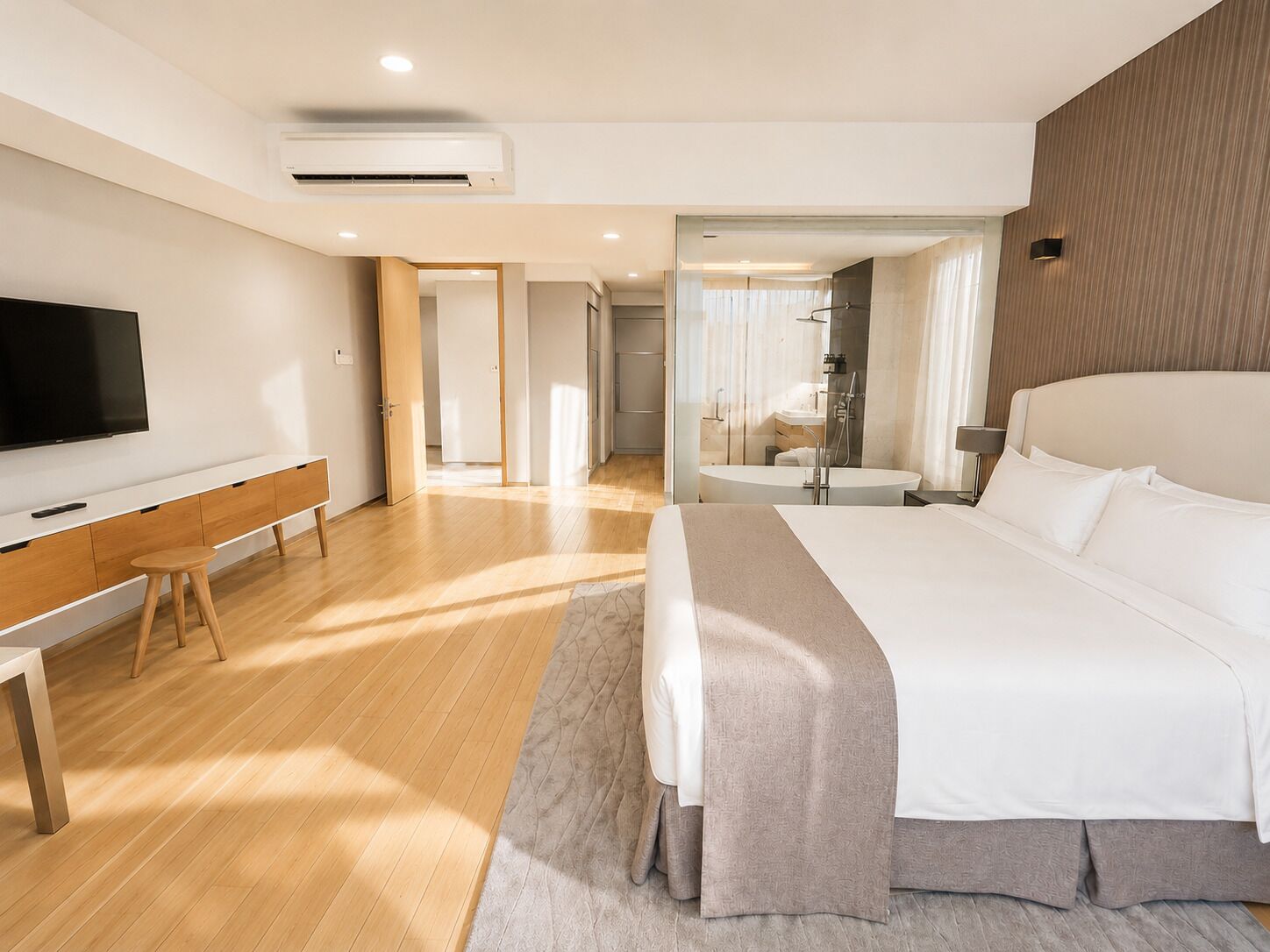 A modern hotel room with a large bed, a desk, a flat-screen TV, and a bathroom with a bathtub and shower.