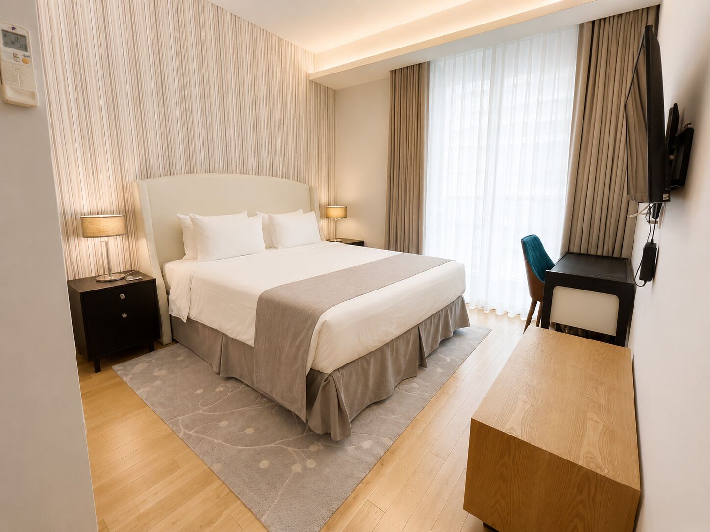 Una habitación de hotel con una cama grande, mesitas de noche, un escritorio y un televisor.