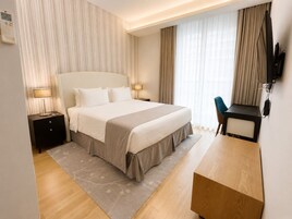 Ein Hotelzimmer mit einem großen Bett, Nachttischen, einem Schreibtisch und einem Fernseher.