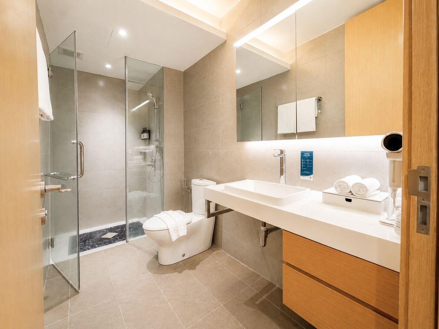 A modern bathroom with a glass-enclosed shower, a toilet, a sink, and a mirror.