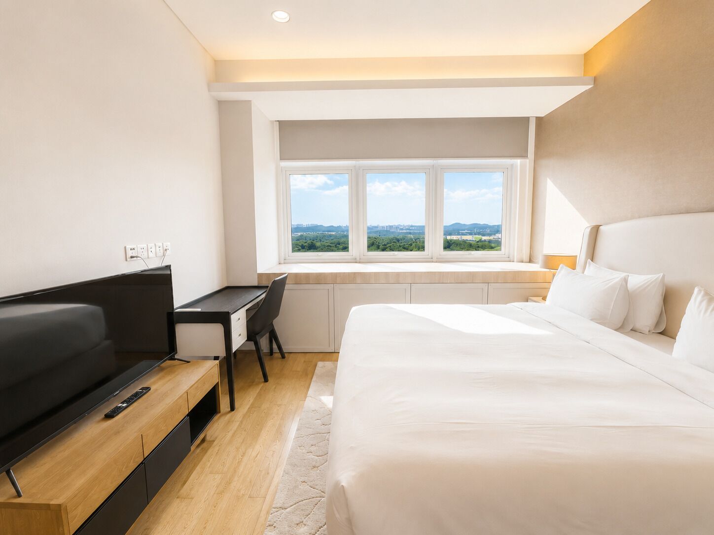 A modern hotel room with a bed, a desk, and a television.