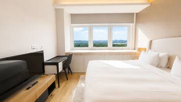 A modern hotel room with a bed, a desk, and a television.