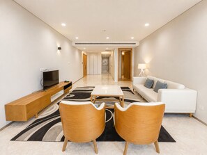 Una sala de estar moderna con televisor de pantalla plana, muebles de madera, un sofá y una lámpara.