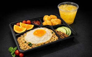 A meal with rice, egg, vegetables, and fruit, served in a black container. - UHF HOTELS & RESORTS PINETREE (Iskandar Puteri)