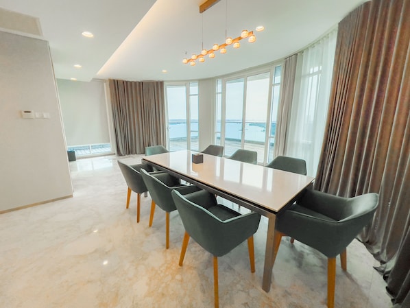A modern conference room with a large table and chairs, large windows with curtains, and a view of the sea. - UHF HOTELS & RESORTS PINETREE (Iskandar Puteri)