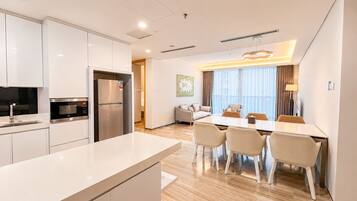 A modern kitchen with a refrigerator, microwave, and sink. There is a dining area with a table and chairs.