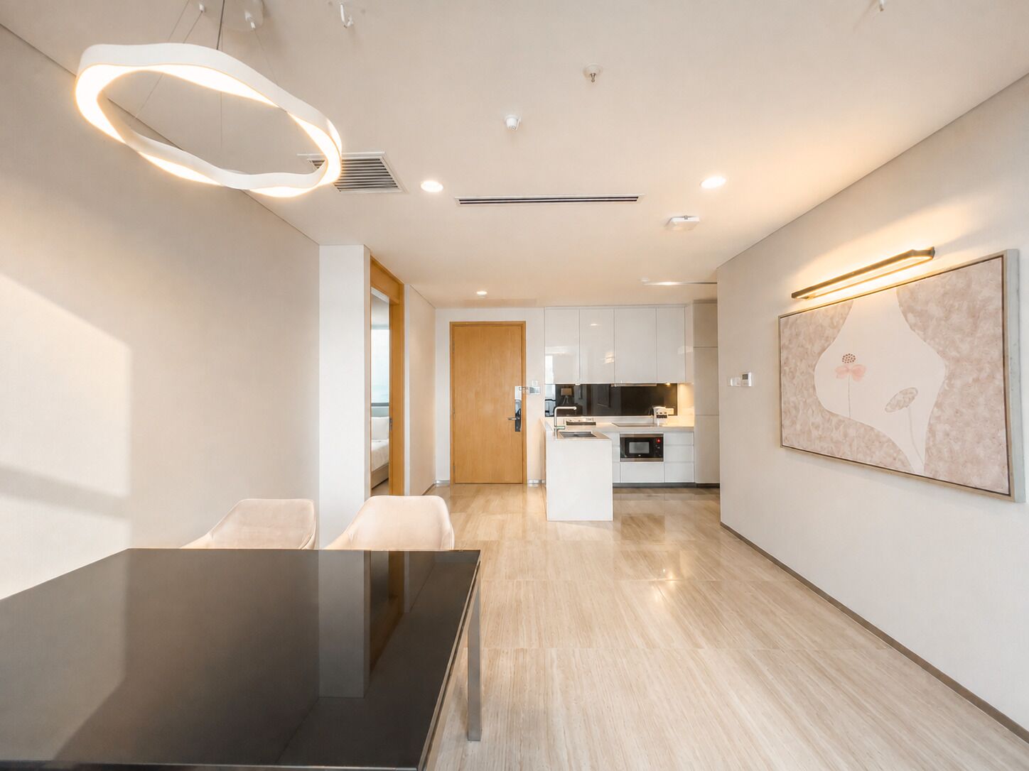 A modern kitchen with white cabinets, a central island, and a dining area with a glass table.