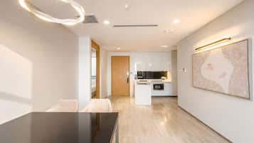 A modern kitchen with white cabinets, a central island, and a dining area with a glass table.