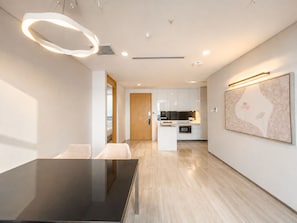 A modern kitchen with white cabinets, a central island, and a dining area with a glass table.