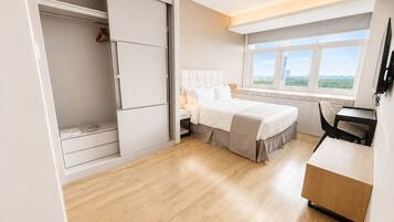 Une chambre d’hôtel comprenant un lit, une table de chevet, un bureau et une fenêtre donnant sur l’extérieur.