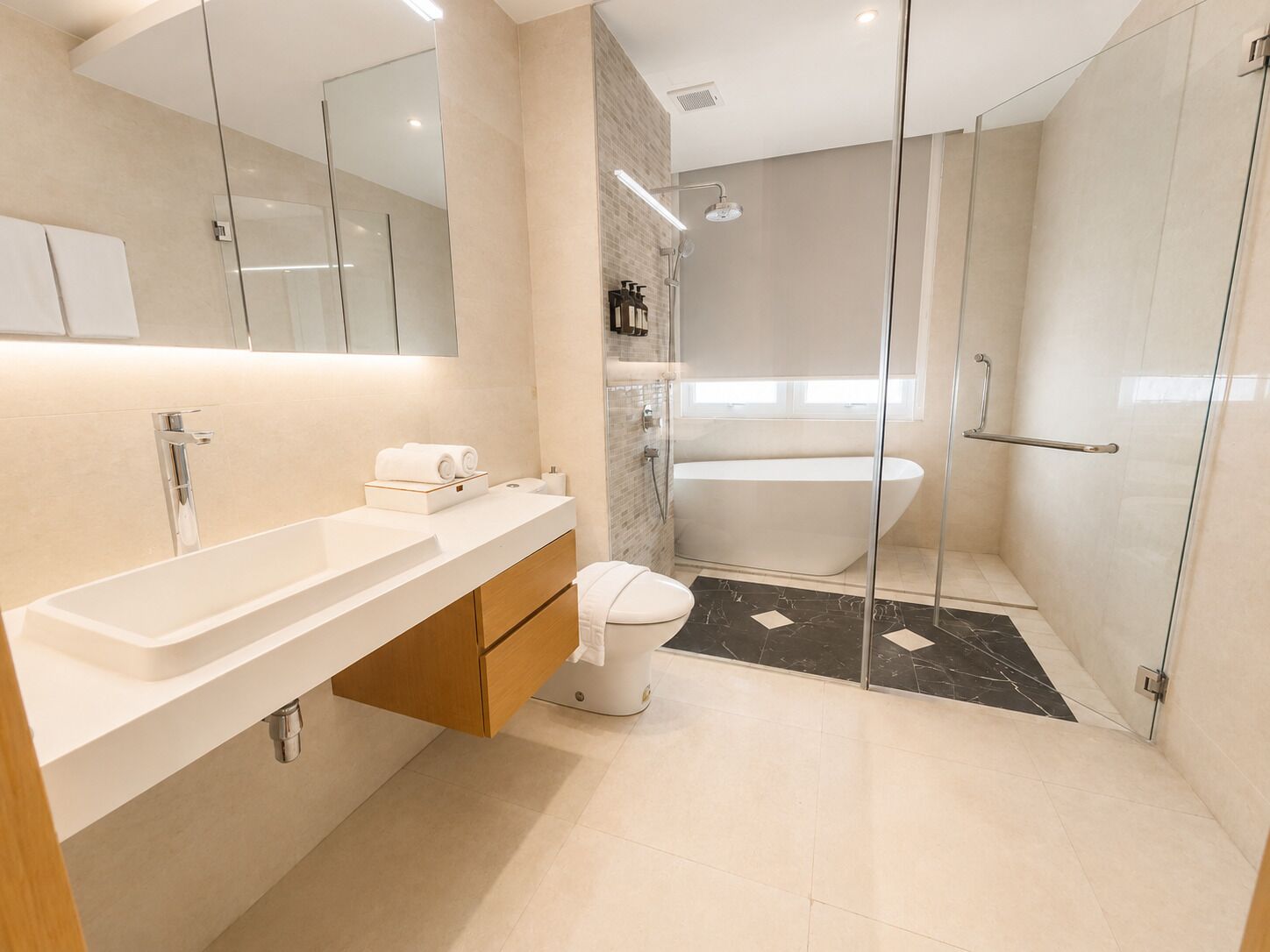 A modern bathroom with a glass shower enclosure, a freestanding bathtub, and a vanity with a sink and mirror.