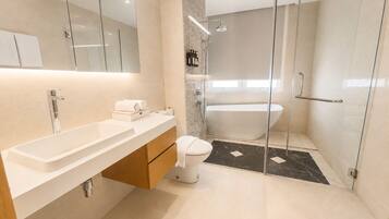 A modern bathroom with a glass shower enclosure, a freestanding bathtub, and a vanity with a sink and mirror.